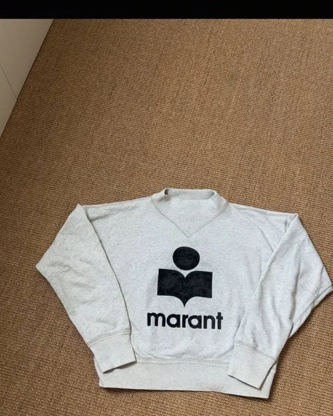 Felpa Isabel Marant grigia appoggiata su un pavimento in fibra